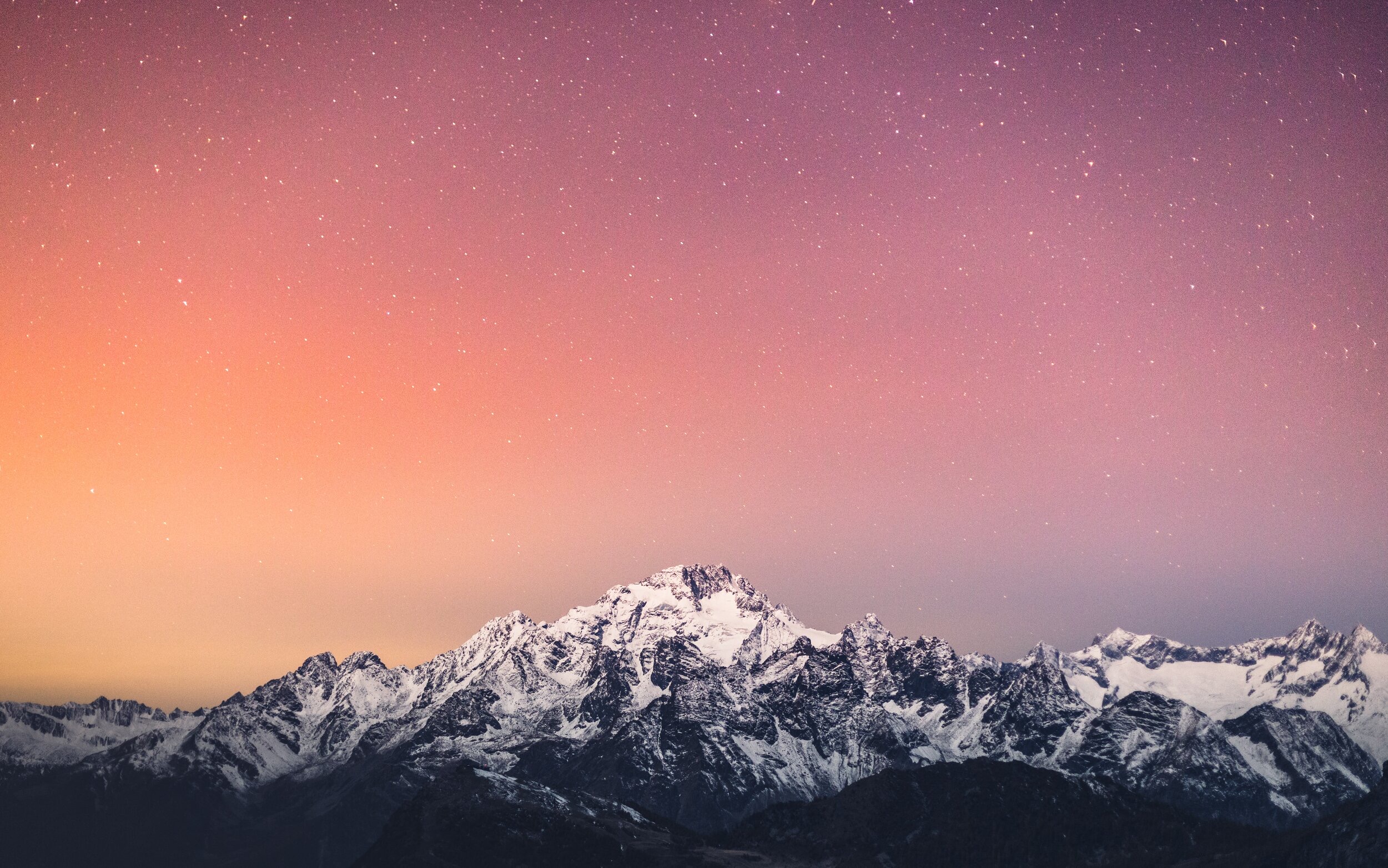 Snow-capped mountains under a pink sunset sky